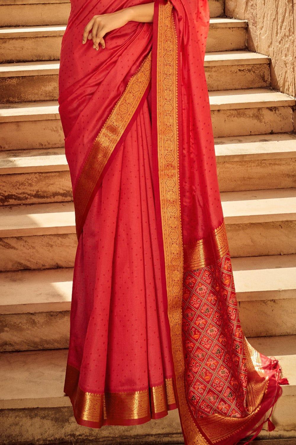 Close-up view of red saree featuring intricate zari work on the pallu and golden border, showcasing traditional Indian craftsmanship