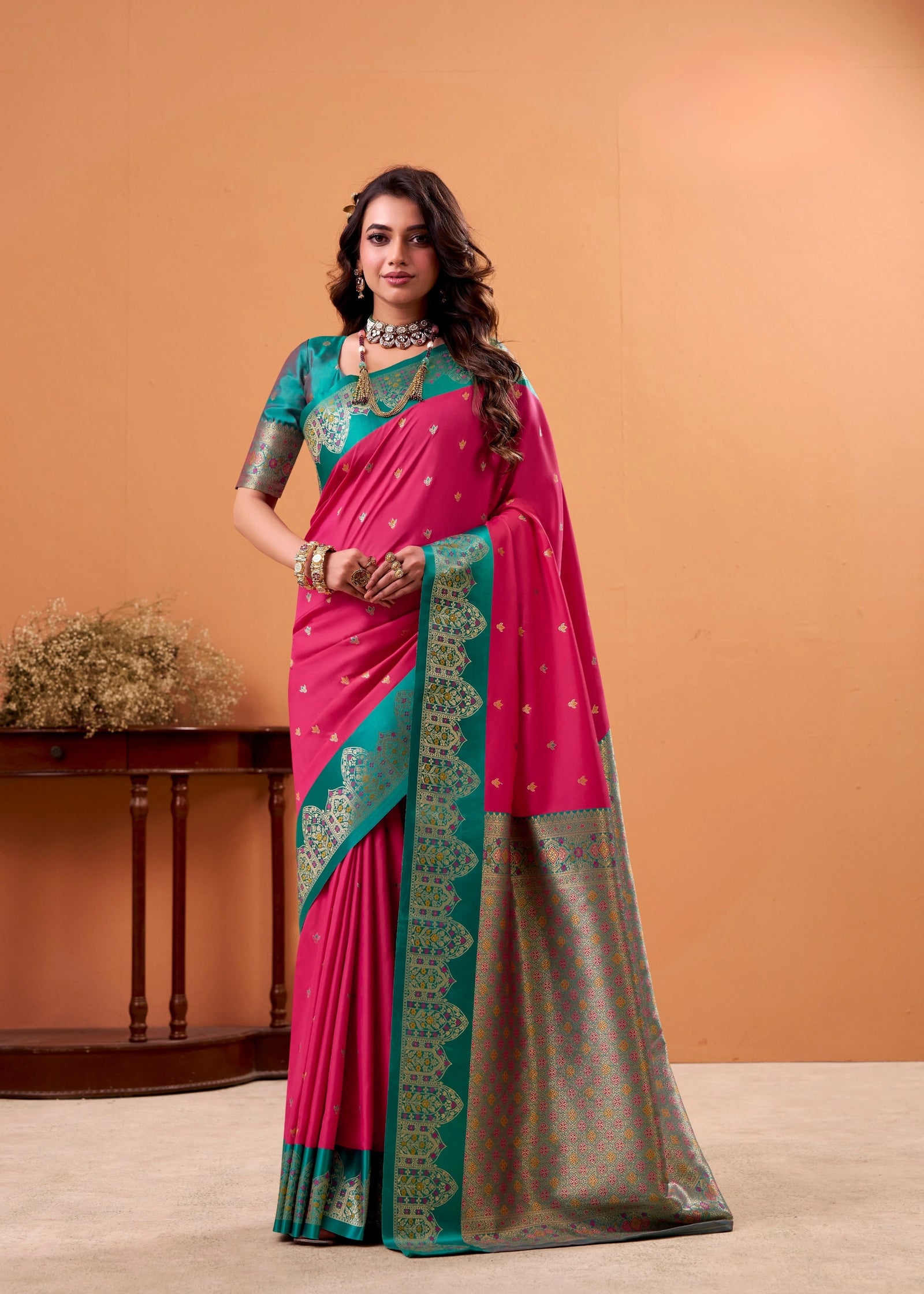 Woman wearing a pink and green saree with a beige background