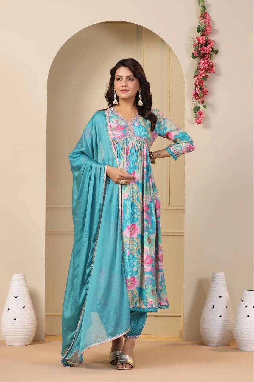 Woman in a floral dress with a turquoise dupatta standing in front of an archway.