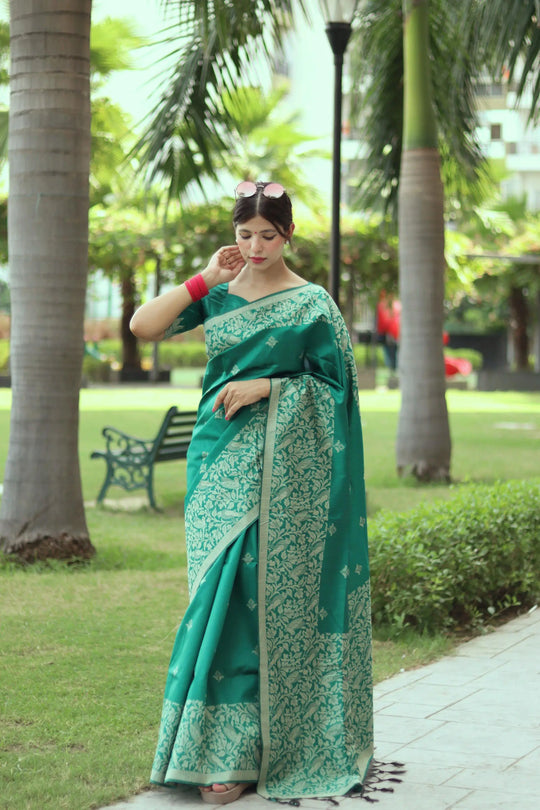 Woman wearing tropical green traditional weaving saree posing gracefully in a lush outdoor setting