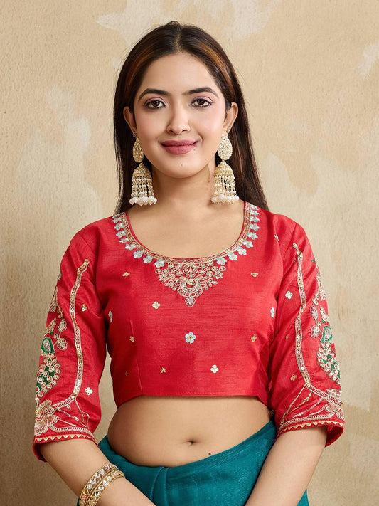 A woman models a vibrant Dark Pink Chiffon Silk Saree with scattered embellishments. The saree has a wide, intricate silver embroidery border. She wears a heavily embroidered dark green blouse and accessorizes with silver jewelry, posing indoors.