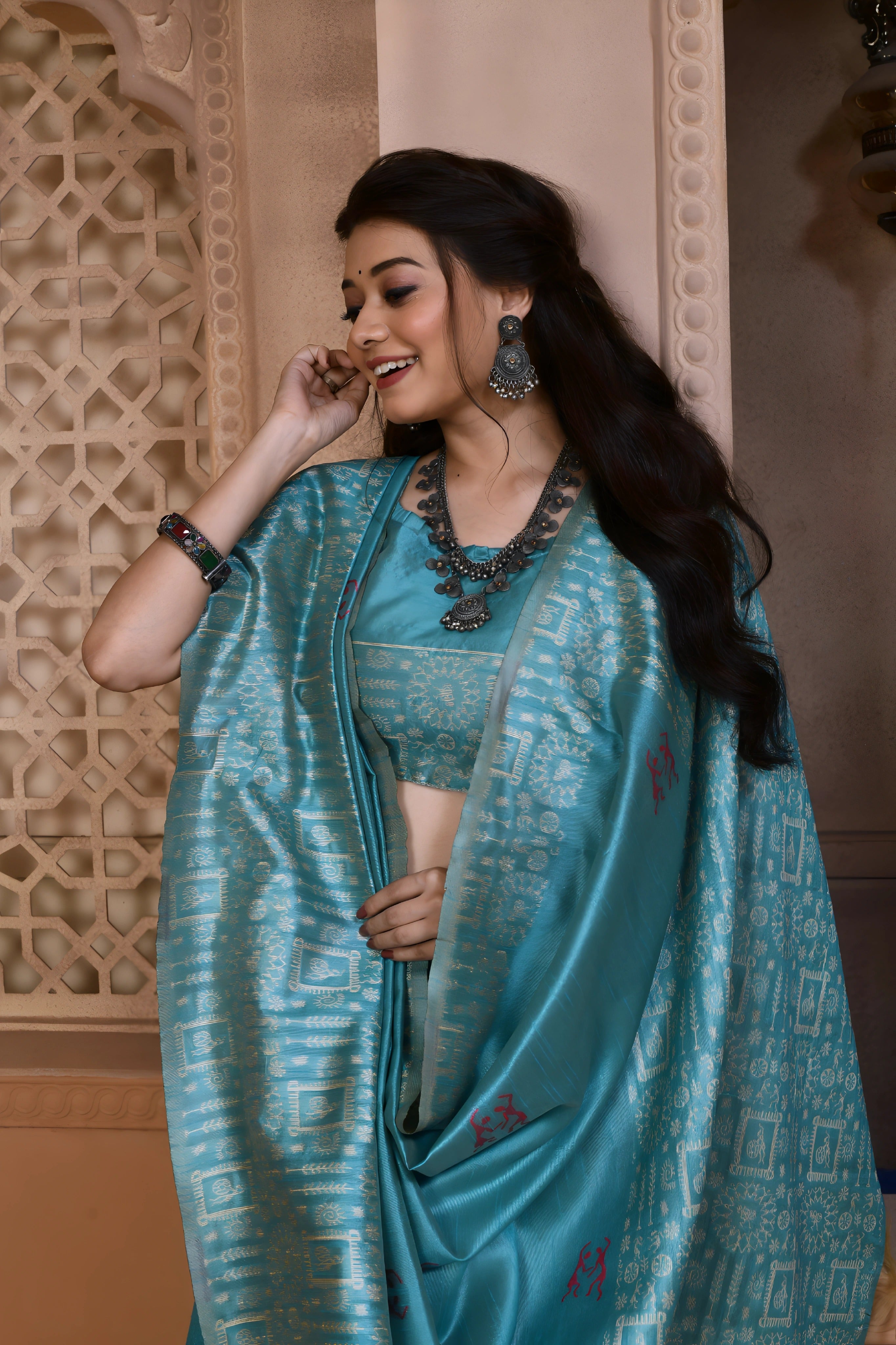 A woman models a striking Sky Blue Banglori Raw Silk Saree. The pallu and border feature dense, traditional Kalamkari-style weaving in a lighter blue metallic thread. She wears a sleeveless blue blouse and heavy oxidized silver or dark gemstone jewelry, posing in an ornate, traditional setting.