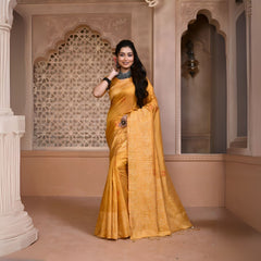 A woman models a vibrant Yellow Banglori Raw Silk Saree. The pallu and border feature dense, tone-on-tone Kalamkari-style weaving in gold Zari. She wears a yellow blouse and heavy dark gemstone jewelry, posing in an ornate, traditional setting.