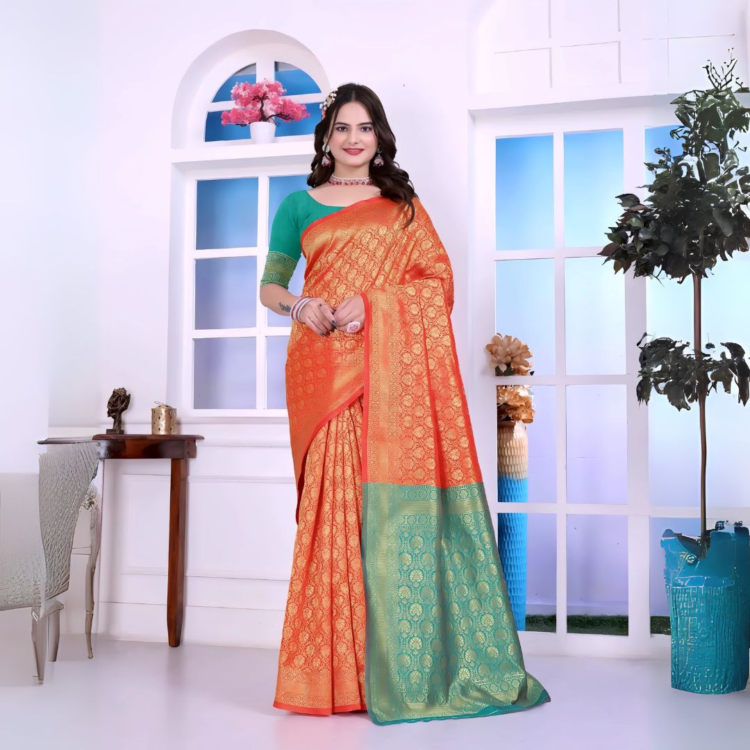 A woman models a striking Orange Banarasi Silk Saree with dense all-over gold Zari weaving. The pallu provides a spectacular contrast in sea green with heavy gold Banarasi weaving. She wears a sea green blouse and gold Kundan jewelry, posing by a window.