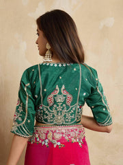 A woman models a vibrant Dark Pink Chiffon Silk Saree with scattered embellishments. The saree has a wide, intricate silver embroidery border. She wears a heavily embroidered dark green blouse and accessorizes with silver jewelry, posing indoors.