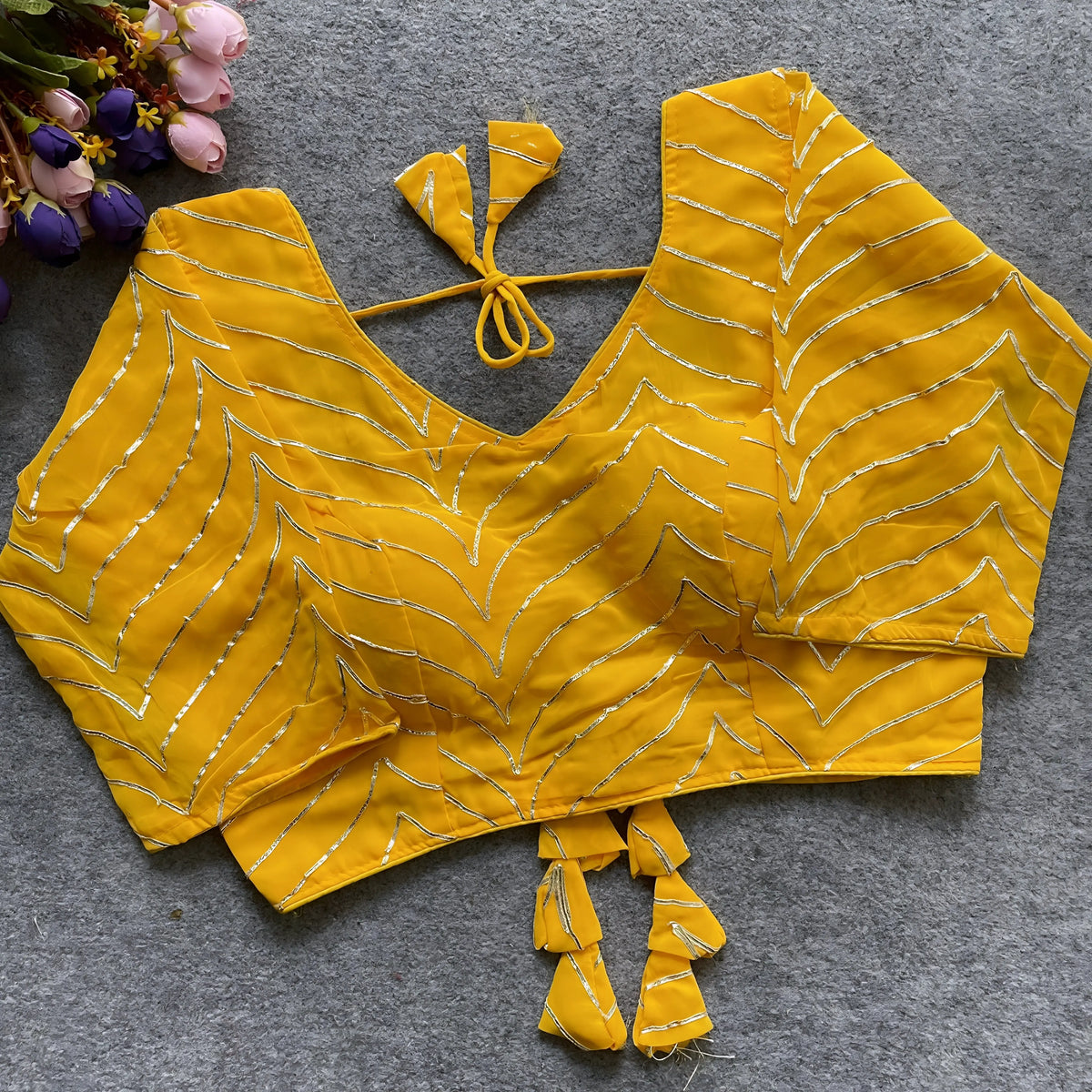 zYellow designer blouse with silver thread embroidery, deep back neckline, and stylish tassel tie detailing.