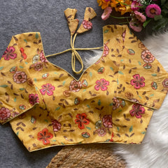 Yellow floral embroidered padded blouse with back tie detail, displayed on a grey surface with artificial flowers and white fur in the background.