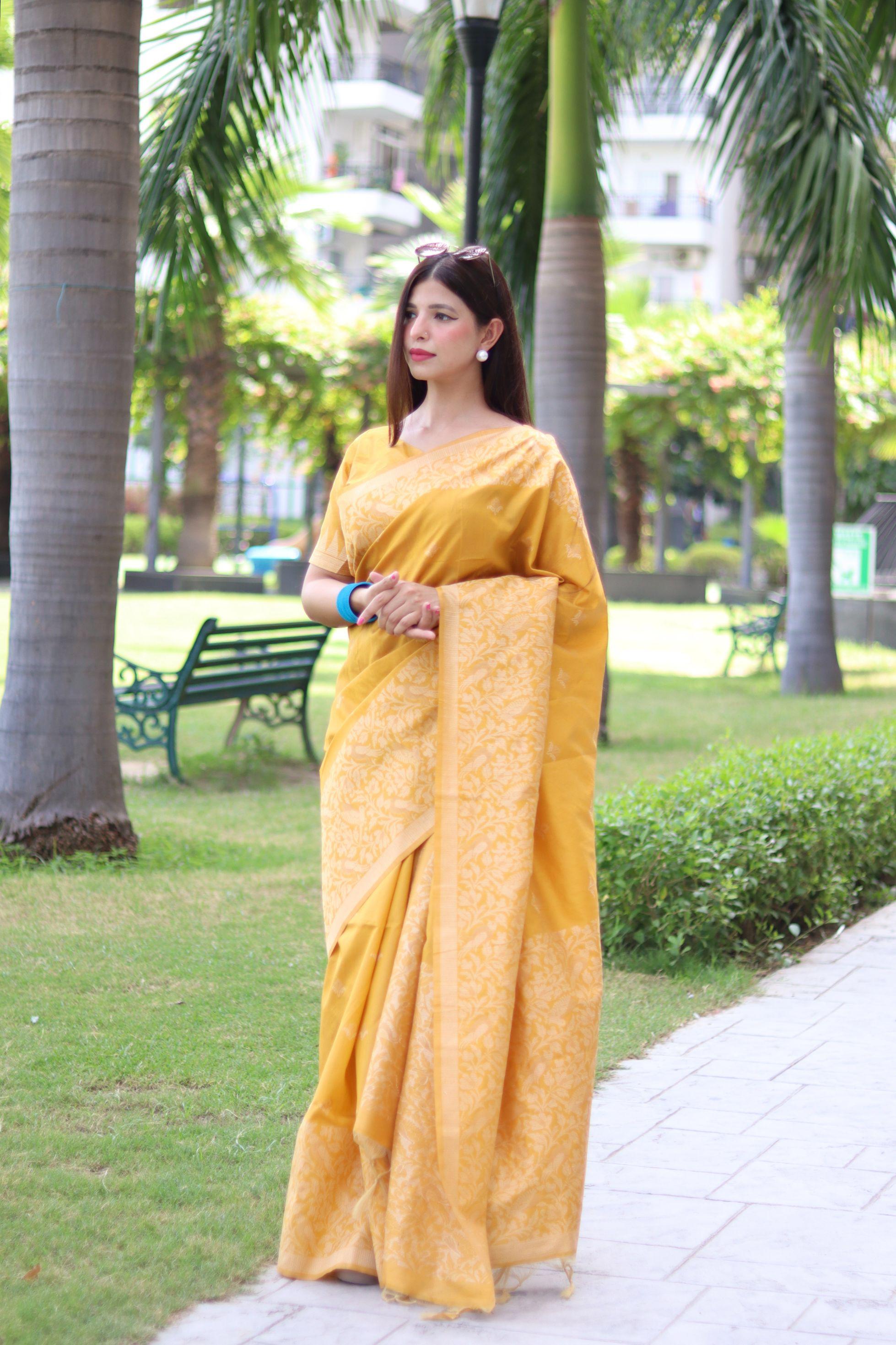 Woman in yellow traditional weaving saree posing gracefully in a garden setting