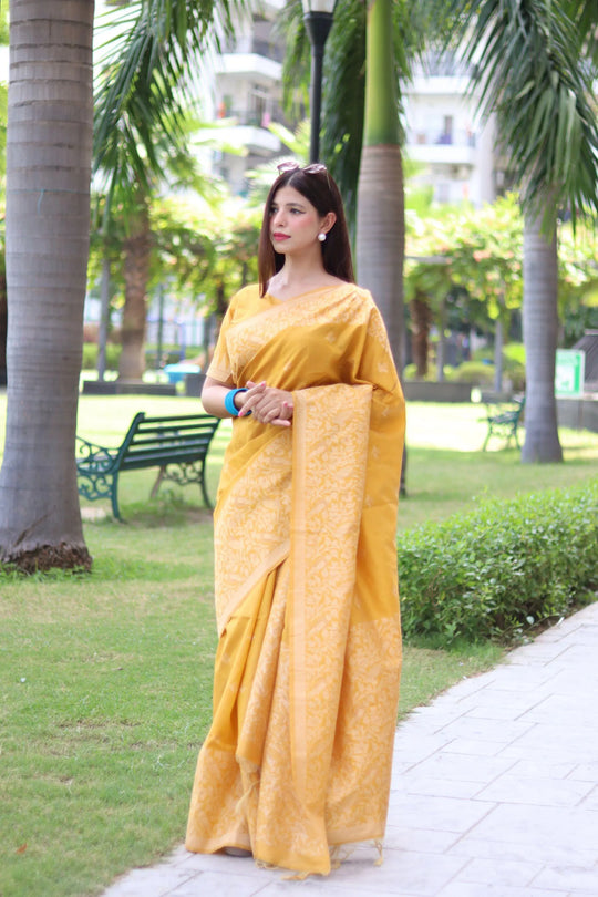 Woman in yellow traditional weaving saree posing gracefully in a garden setting