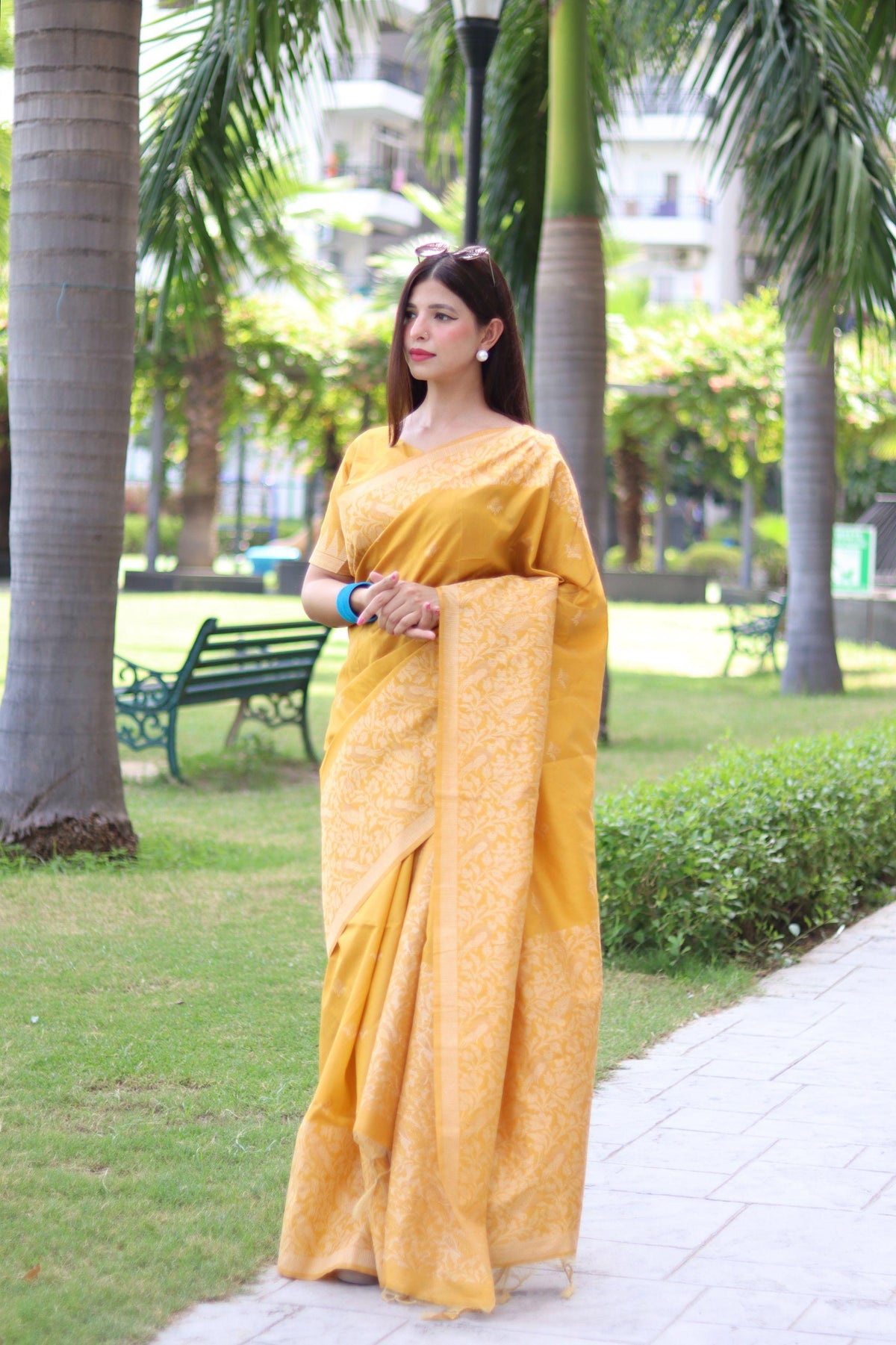 Woman in yellow traditional weaving saree posing gracefully in a garden setting